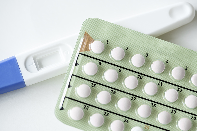 Close-up of a birth control pill pack beside a home pregnancy test.